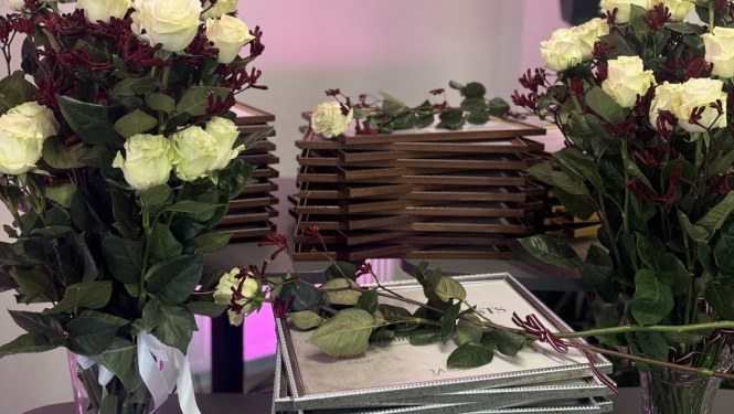 Attēlā redzami ziedi un diplomi