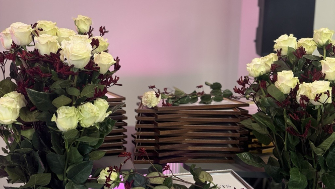 Attēlā redzami ziedi un diplomi