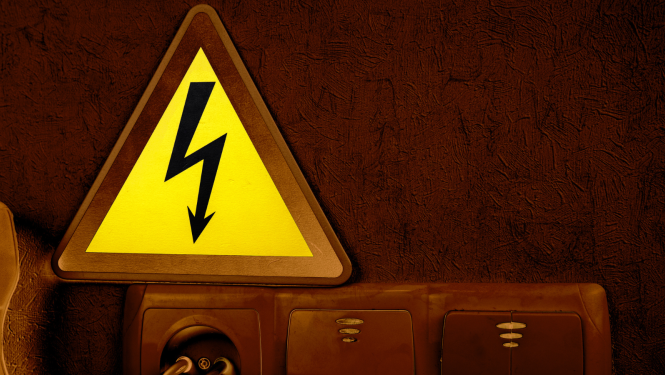 Attēlā redzams dzeltena brīdinājuma zīme, kur iekšā ir zibens zīme, kā brīdinājums