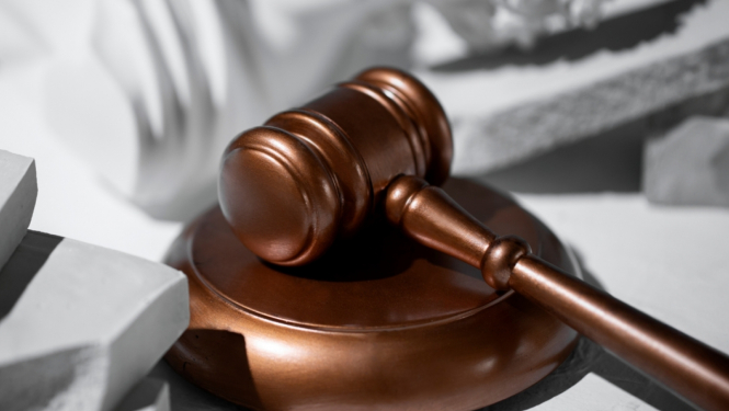 attēlā tiesas āmurs stāv uz galda