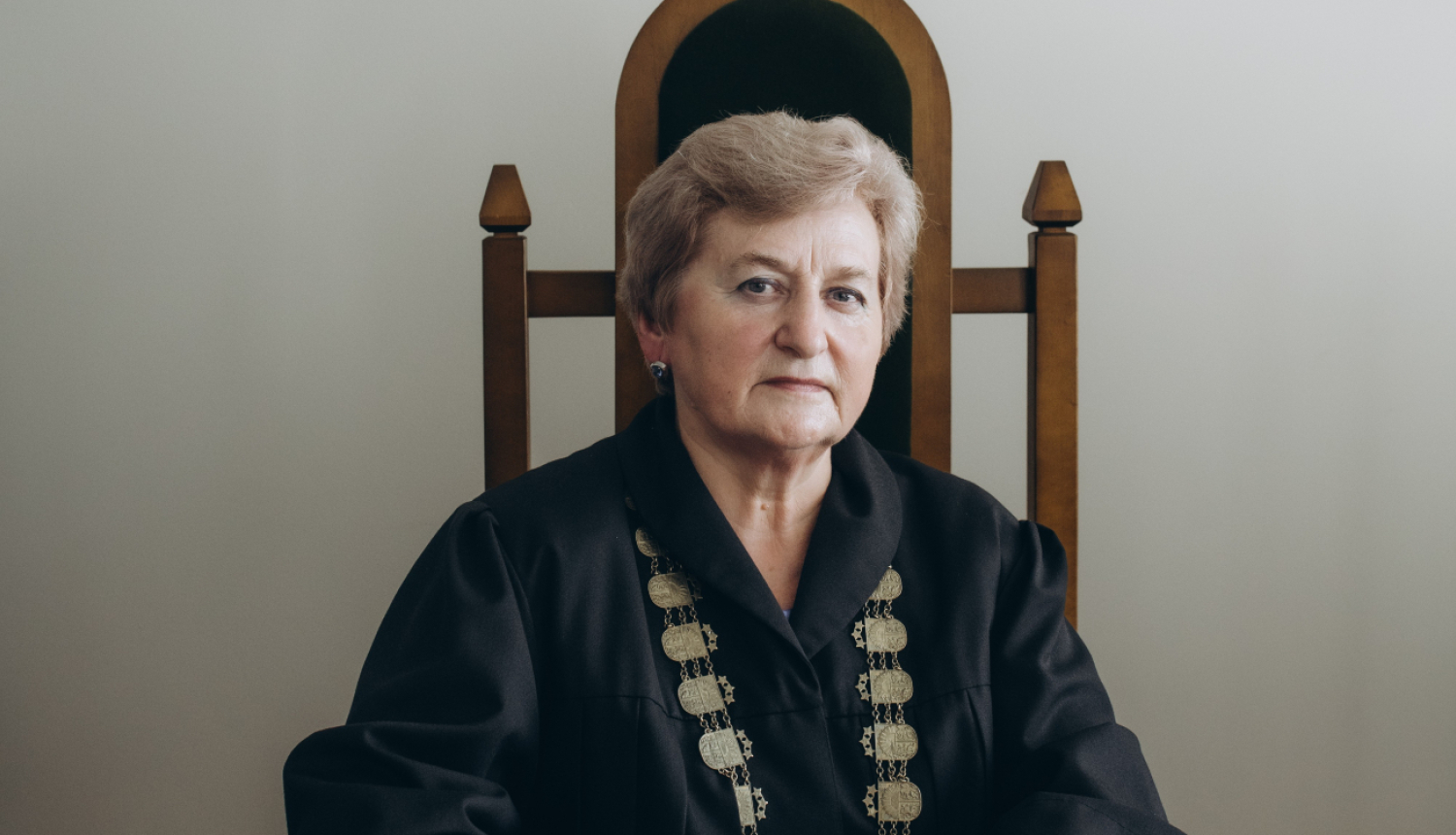 Attēlā tiesnese sēž tiesas zālē