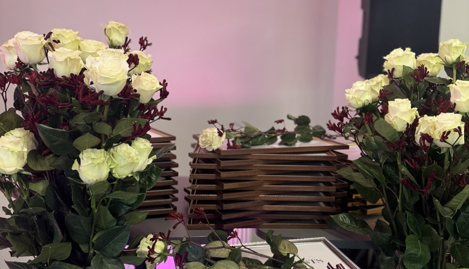 Attēlā redzami ziedi un diplomi