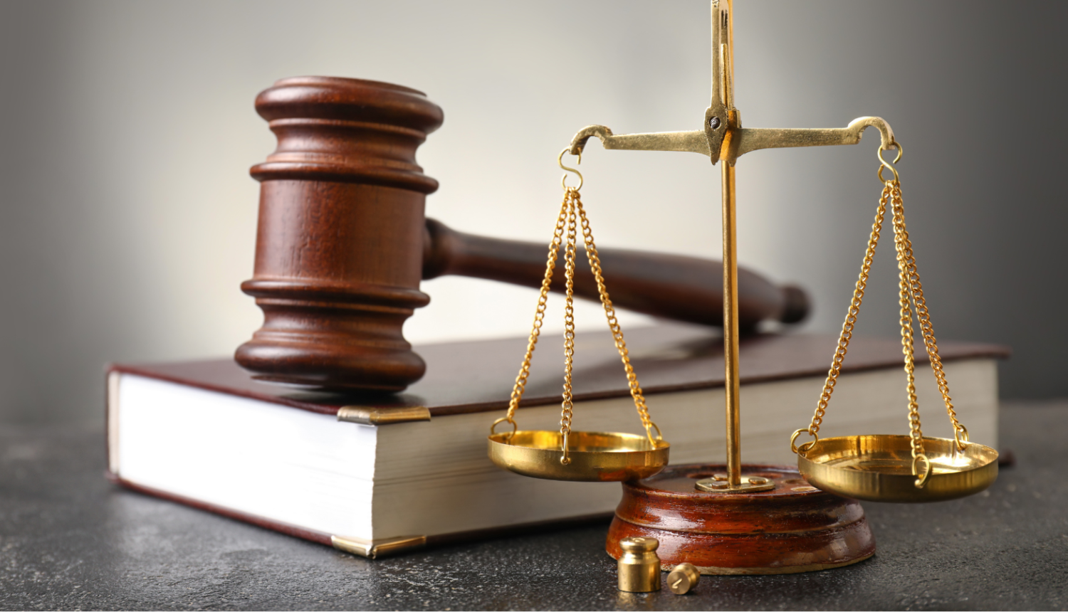 Attēlā redzams tiesneša āmurs, svari un grāmata - attēlam ilustratīva nozīme