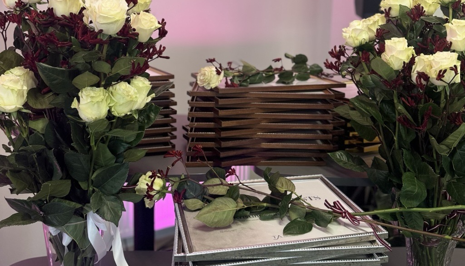 Attēlā redzami ziedi un diplomi